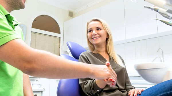 Boldog mosolygó, szőke nő kezet a férfi fogorvos-fogászati klinika — Stock Fotó