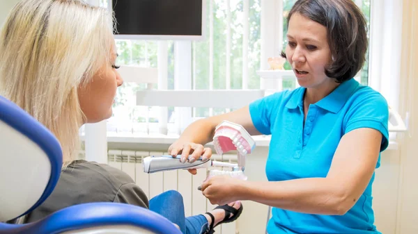 Retrato de dentista feminina mostrando seu paciente como limpar adequadamente os dentes — Fotografia de Stock