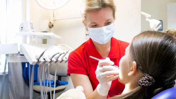 Retrato del dentista pediátrico femenino en máscara que examina los dientes de los pacientes — Foto de Stock