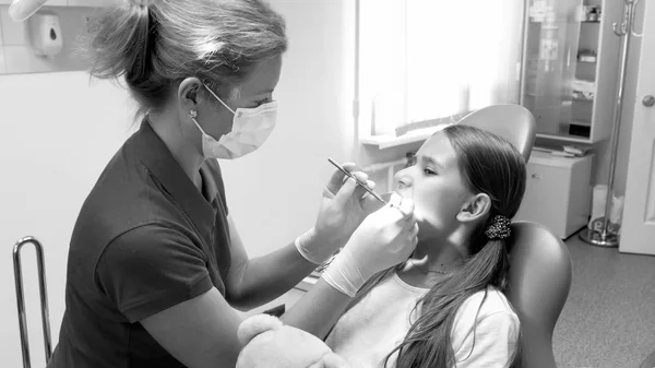 Zwart-wit beeld van vrouwelijke pediatrische tandarts inspectie meisjes tanden — Stockfoto