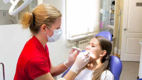 Jovem dentista examinando pacientes dentes com instrumentos especiais — Fotografia de Stock