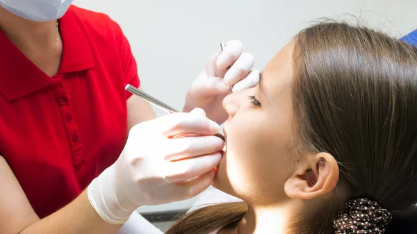 Close-up beeld van tandarts handen in beschermende handschoenen inspecteren van de mondholte in meisjes mond — Stockfoto