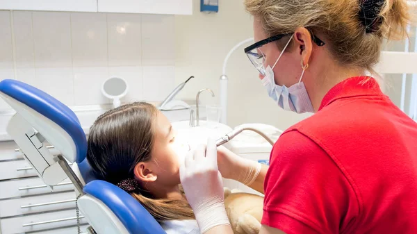 Dentista pediátrico feminino em máscara protetora e óculos tratando dentes meninas — Fotografia de Stock