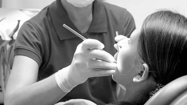 Närbild svart och vit bild av tandläkare inspektera patientens tänder med specialverktyg — Stockfoto