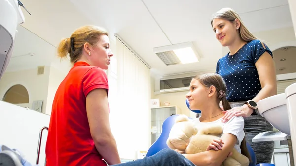 Jovem mãe sorridente conversando com dentista pediátrico na clínica — Fotografia de Stock