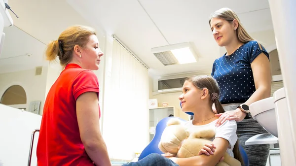 Dentista pediátrico feminino explicando treting dentes para meninas mãe — Fotografia de Stock