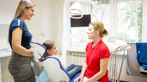 Kvinnliga tandläkare talar med flickan och hennes mamma om tänder som behandling av — Stockfoto
