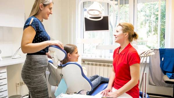 Mosolygó fiatal anya beszél a gyermekorvosi fogorvos fogorvos irodájában — Stock Fotó