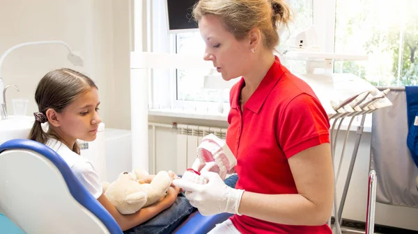 Potret dokter gigi anak menjelaskan perawatan gigi kepada pasiennya — Stok Foto