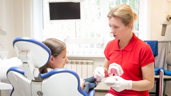 Kvinnliga tandläkare visar på tänder modell hur man ordentligt rena tänder — Stockfoto