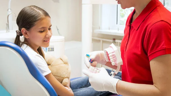 Dentista pediátrico usando modelo de mandíbula para explicar como escovar adequadamente os dentes — Fotografia de Stock