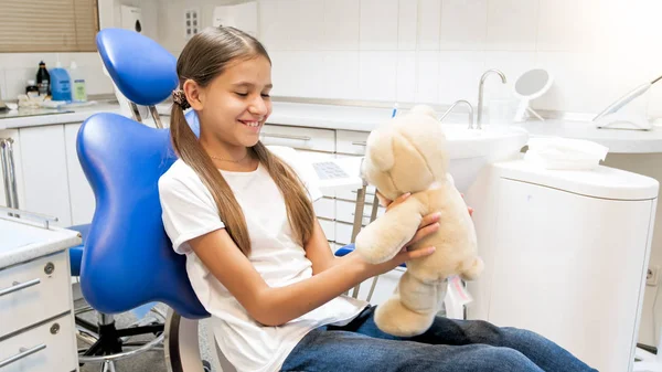 Ritratto di ragazza carina sorridente che gioca con l'orsacchiotto nello studio dentistico — Foto Stock