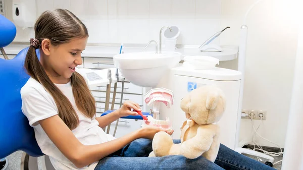 Onun oyuncak ayı diş dişçi ofisinde temizlik eğitmek gülümseyen kız portresi — Stok fotoğraf