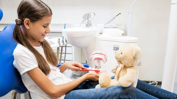 Menina bonito explicando importância da higiene dos dentes para seu ursinho de pelúcia — Fotografia de Stock