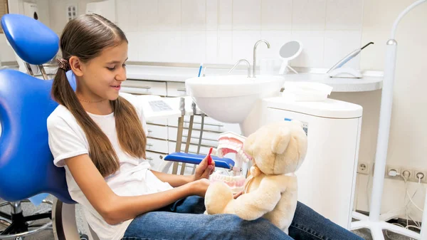 Liten flicka sitter i tandläkare stol och leker med hennes Nalle — Stockfoto