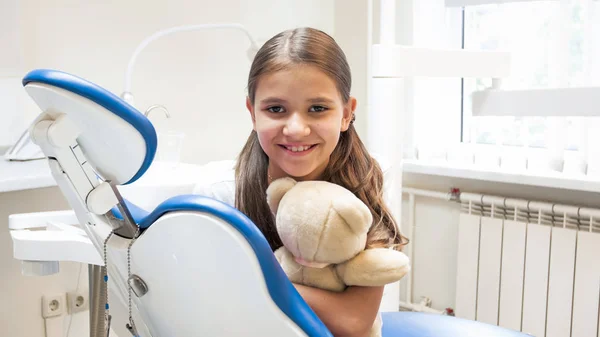 Retrato de menina sorridente bonito sentado na cadeira do dentista e olhando na câmera — Fotografia de Stock