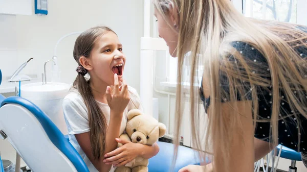 Ung mamma tittar på hennes döttrar tänder efter tänder treatening i tandläkare kontor — Stockfoto