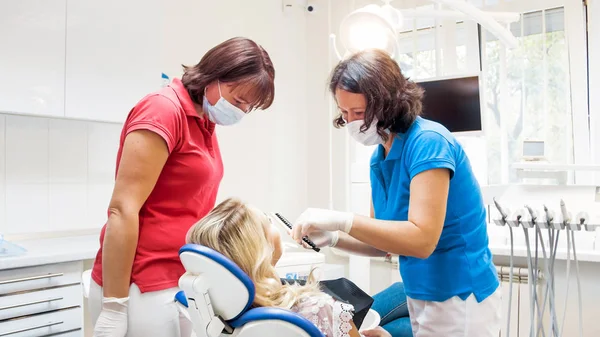 Retrato de dentista e assistente conversando com paciente do sexo feminino na clínica — Fotografia de Stock