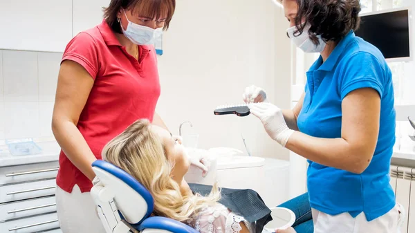 Dentista e assistente preparando paciente feminino para clareamento dos dentes — Fotografia de Stock