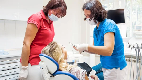 Dentista profissional preparando paciente feminino para o procedimento de clareamento dos dentes — Fotografia de Stock