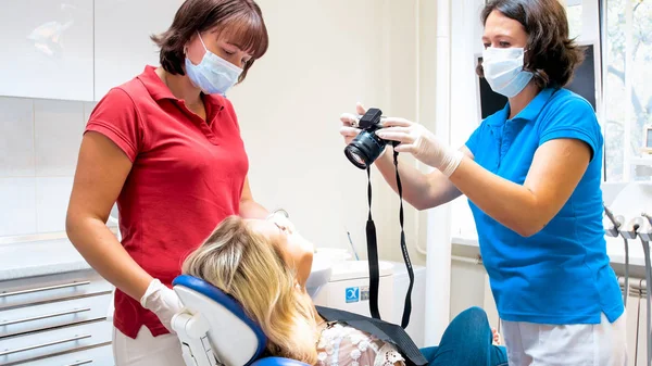 Dentista feminina usando câmera dgital para fazer fotografia de pacientes dentes após o tratamento — Fotografia de Stock