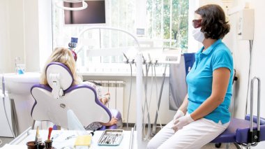 Hastayla fotopolimer yordamla diş beyazlatma sırasında oturan kadın diş hekimi