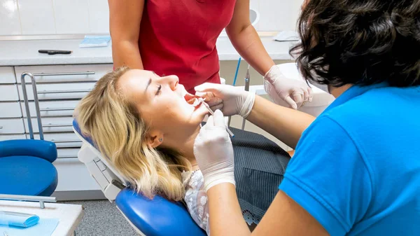 Close-up beeld van vrouwelijke tandarts controle patiënten tanden met spiegel — Stockfoto