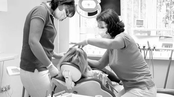 Schwarz-Weiß-Bild des Zahnarztes und Assistenten bei der Arbeit mit dem Patienten — Stockfoto
