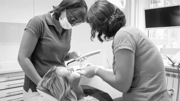Imagem em preto e branco do dentista e assistente de tratamento do paciente na clínica — Fotografia de Stock