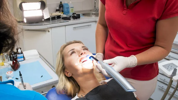 Retrato de close-up do dentista assistente segurando lâmpada ultravioleta na boca pacientes — Fotografia de Stock
