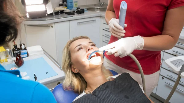 Close-up beeld van tandarts assistent verwijderen speeksel uit de mond van de patiënten met speciale zuigen buis — Stockfoto