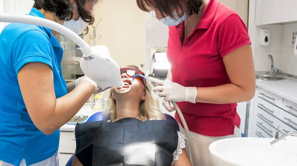 Retrato de dentista assistente segurando ejetor salive durante o procedimento de clareamento dos dentes — Fotografia de Stock