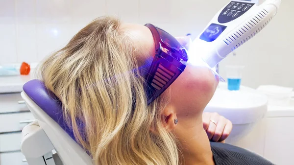 Closeup portret van de jonge vrouw haar tanden met UV-licht in de tandheelkundige kliniek whitening — Stockfoto