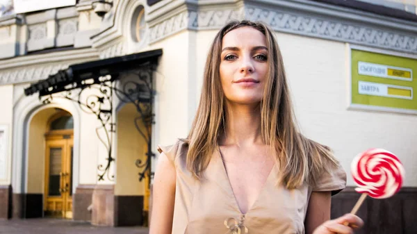 Retrato de una hermosa joven posando con grandes dulces en la calle — Foto de Stock