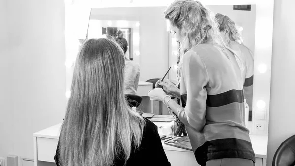 Black and white image of makeup artist applying makeup in visage studio — Stock Photo, Image