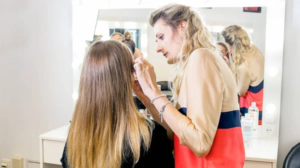 Portrait of young makeup artist working with model in studio — Stock Photo, Image