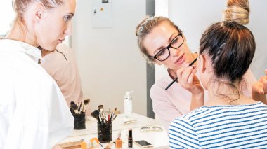 Öğrenci öğretmenine güzellik salonda modelleri yüzünde makyaj uygulamak olarak seyir portresi