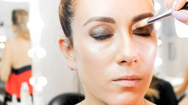 Closeup image of makeup artist painting models eyes with brush — Stock Photo, Image