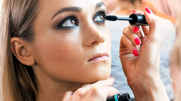 Closeup image of profesinal makeup artist painting models eyelashes with mascara — Stock Photo, Image