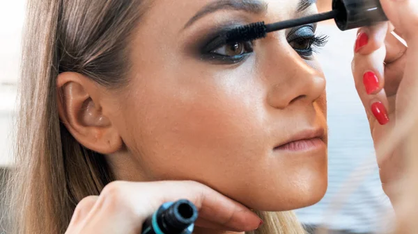 Macro image of makeup artist painting models eyes with mascara — Stock Photo, Image