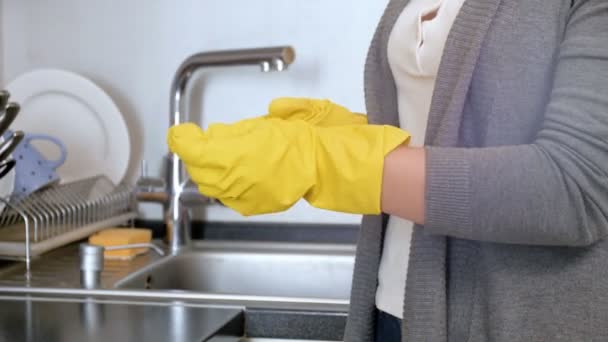 Primer plano 4k metraje de ama de casa joven quitándose guantes de látex amarillo después de hacer las tareas domésticas en la cocina — Vídeo de stock