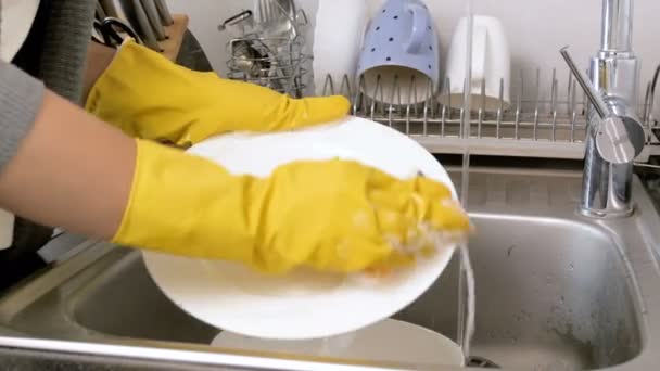Съемки крупным планом, на которых домохозяйка смывает моющее средство с посуды в кухонной раковине — стоковое видео