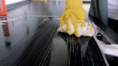 Closeup 4k görüntüleri kamera aşağıdaki el sünger çamaşır cam yüzey elektrikli soba mutfak üzerinde tutan sarı lastik eldiven