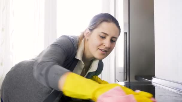 Primo piano 4k video di giovane donna sorridente pulizia fornello elettrico a induzione sulla cucina — Video Stock