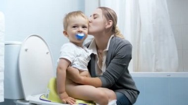 mutlu genç anne tuvalet kullanarak onun şirin bebek çocuk öğretim 4 k görüntüleri