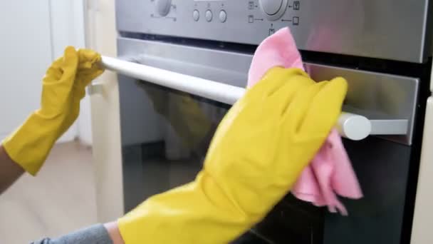 Gros plans 4k de jeune femme en gants de caoutchouc jaune nettoyant poignée de four électrique — Video