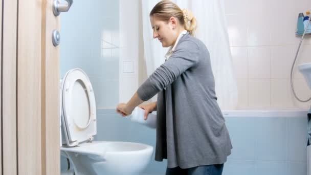 Imágenes de 4k de una mujer joven vertiendo detergente antibacteriano en el inodoro mientras hace las tareas domésticas — Vídeo de stock