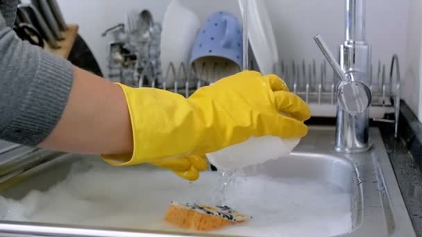 Крупный план замедленной съемки домохозяйки в резиновых перчатках, моющей посуду на кухне — стоковое видео
