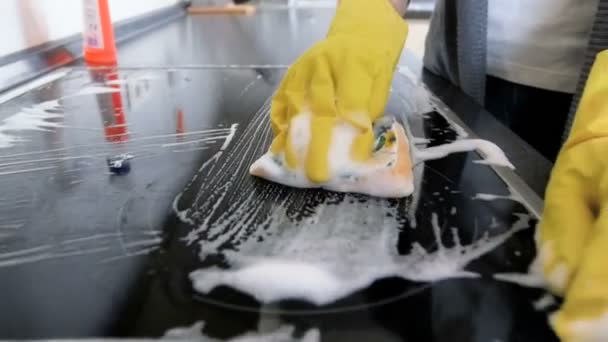 Медленное движение крупным планом видео молодой домохозяйки очистки электроиндукционной печи на кухне с губкой — стоковое видео