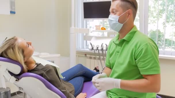 Imágenes de 4k steadycam del dentista masculino que usa eneldo mientras trata los dientes de las pacientes femeninas — Vídeo de stock